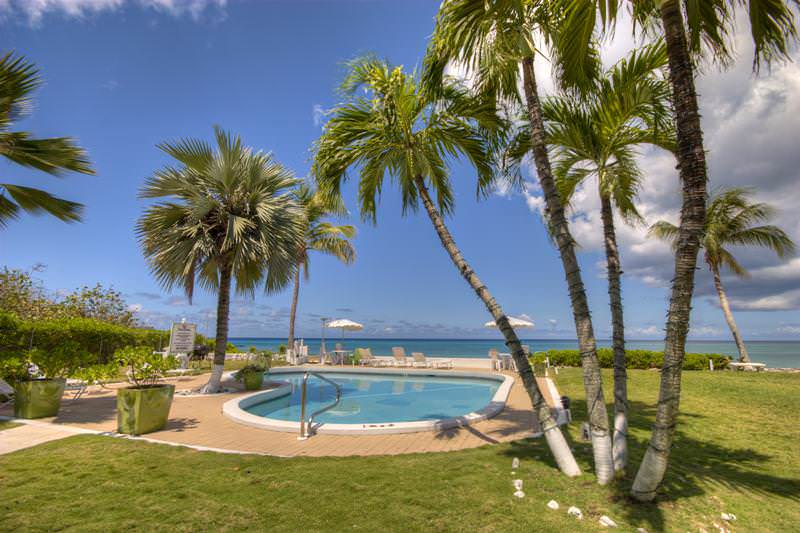 Cocoplum swimming pool with view of the ocean behind it